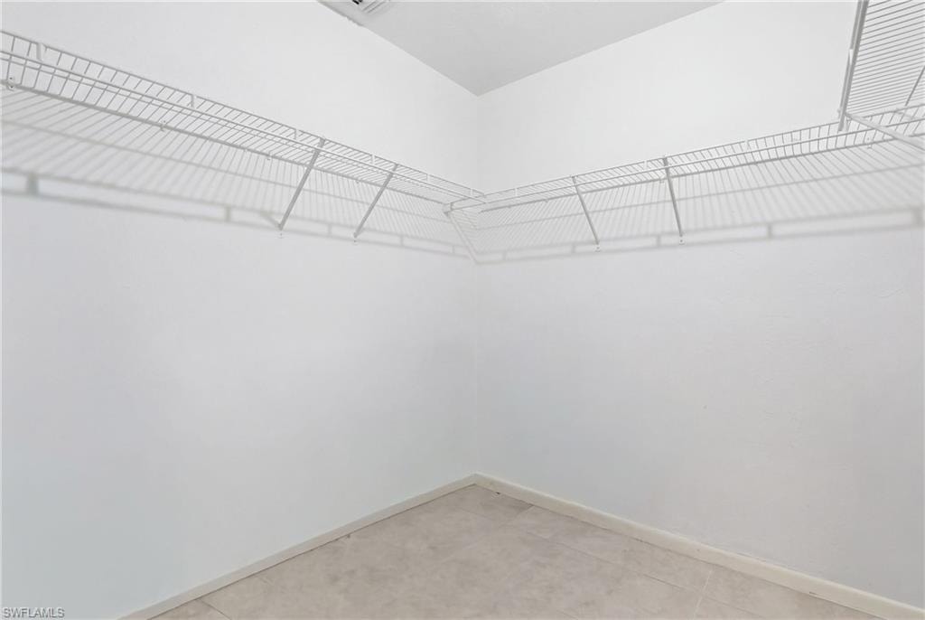 Walk-in closet featuring white wire shelving, light-toned tile flooring, and white painted walls