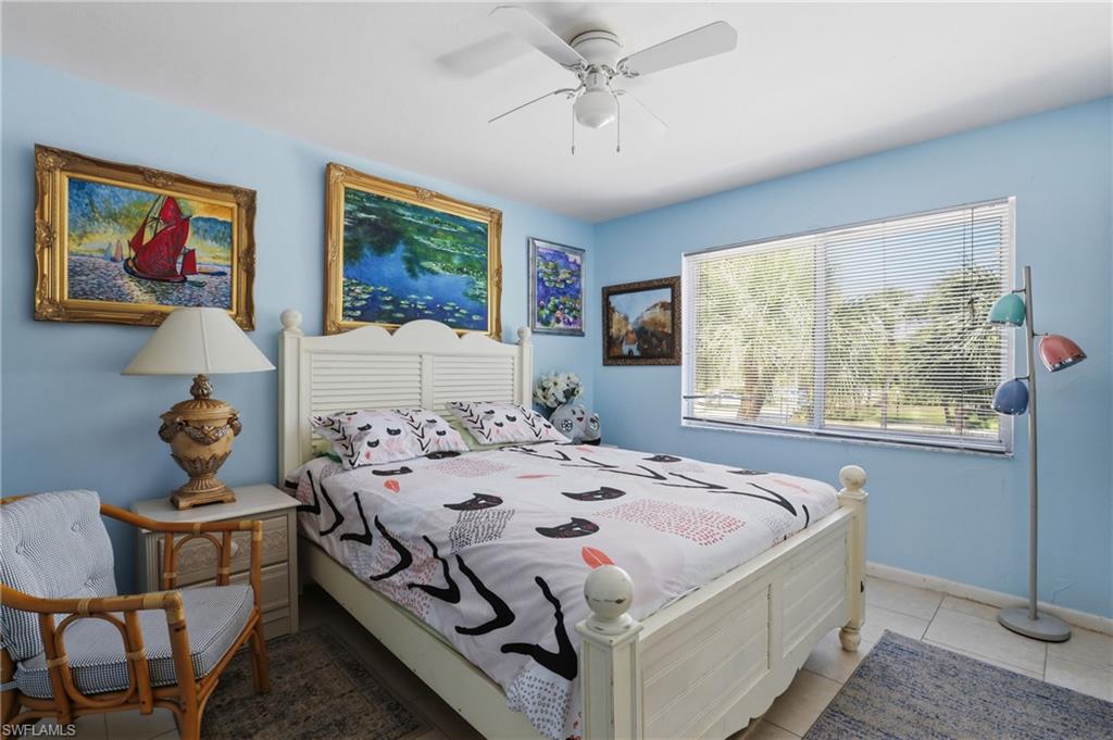 Bedroom featuring a white louvered headboard, tiled flooring, and a large window with blinds