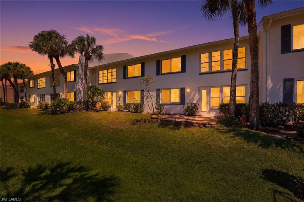 Multi-story white stucco exterior featuring multiple windows with dark shutters