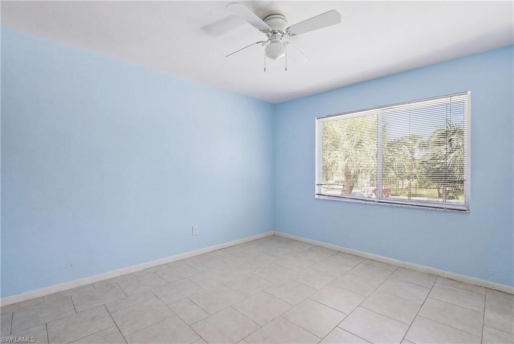 Spacious room featuring tile flooring, a wide window with horizontal blinds, and a ceiling fan with integrated lighting