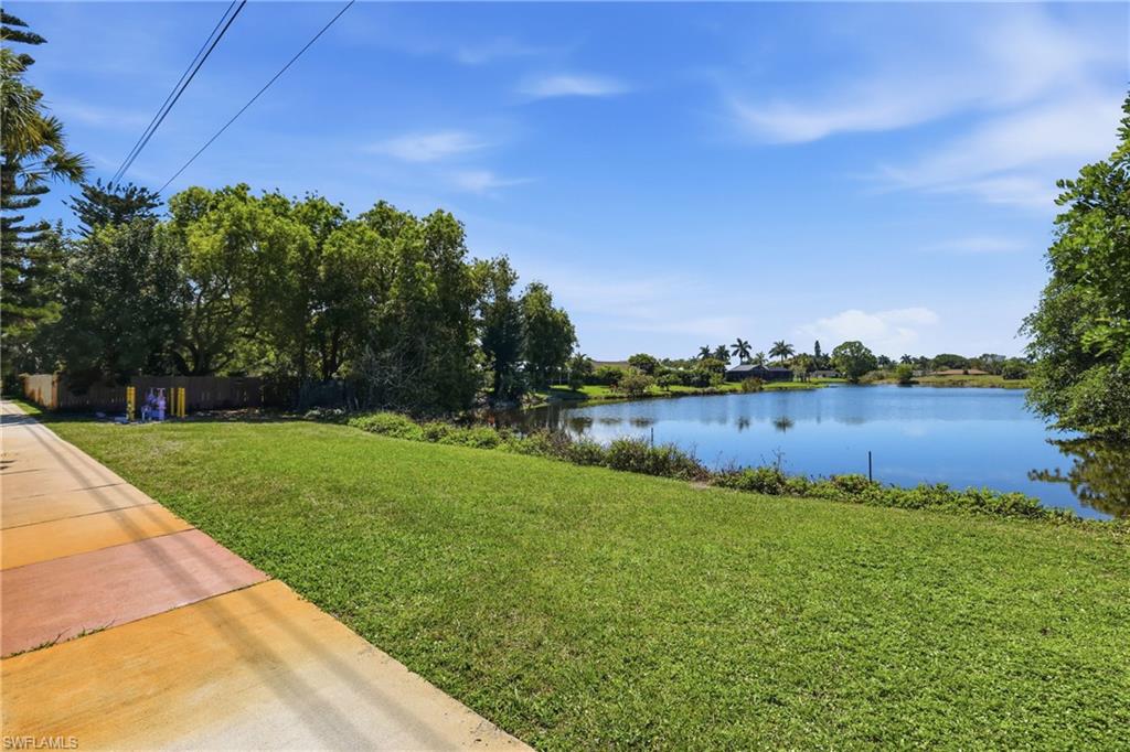Expansive waterfront property featuring a large body of water, mature trees, and a clear blue sky