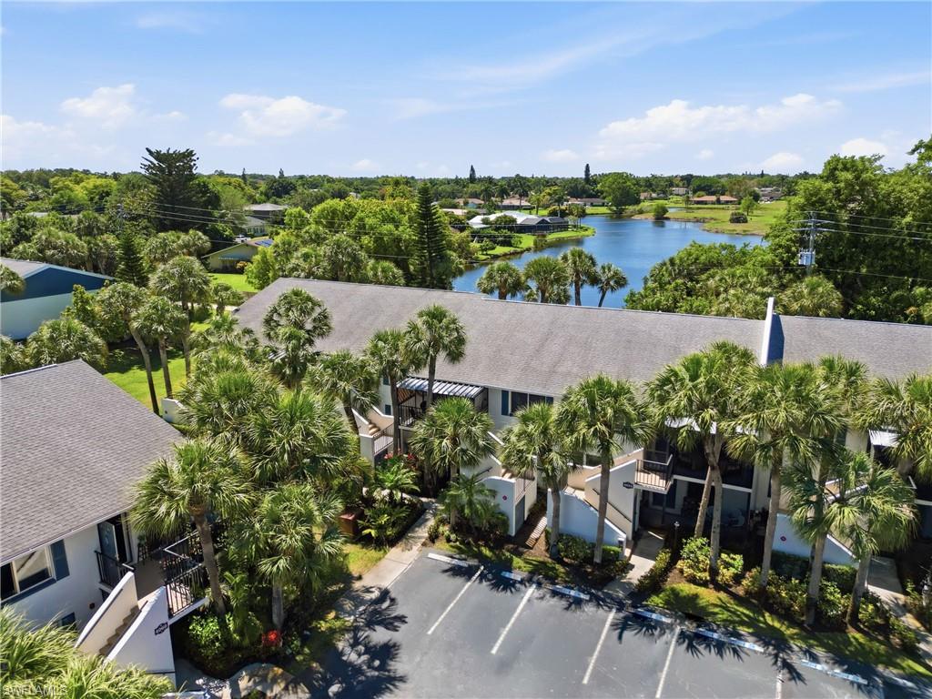 Multi-story property featuring a lake background and abundant palm trees