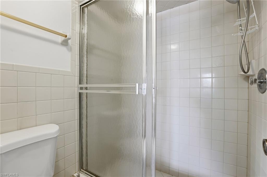 Glass-enclosed shower with white square tile walls and a chrome shower fixture