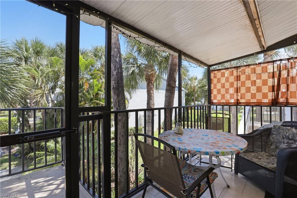 Screened balcony featuring a white corrugated ceiling, dark metal railings, and a partial privacy screen
