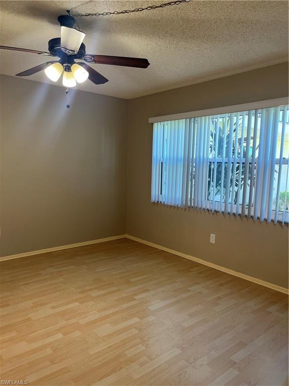 Room featuring wood-finish flooring, a ceiling fan with integrated lighting, and a large window with vertical blinds