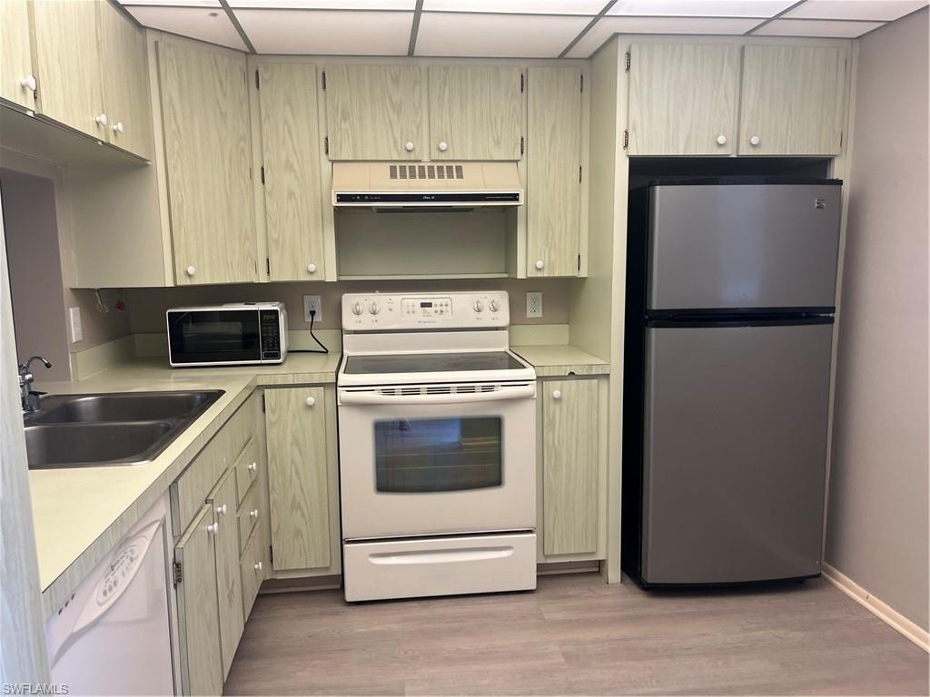Kitchen featuring wrap-around cabinetry, a double basin sink, and a full suite of appliances including a range, dishwasher, and refrigerator