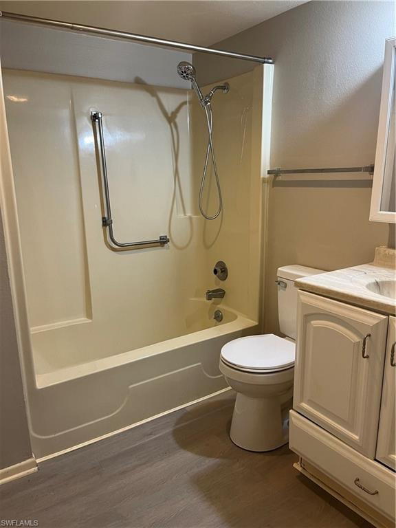Full bathroom featuring a tub/shower combination with a hand-held shower head, a white vanity with a countertop, and gray wood-finish flooring