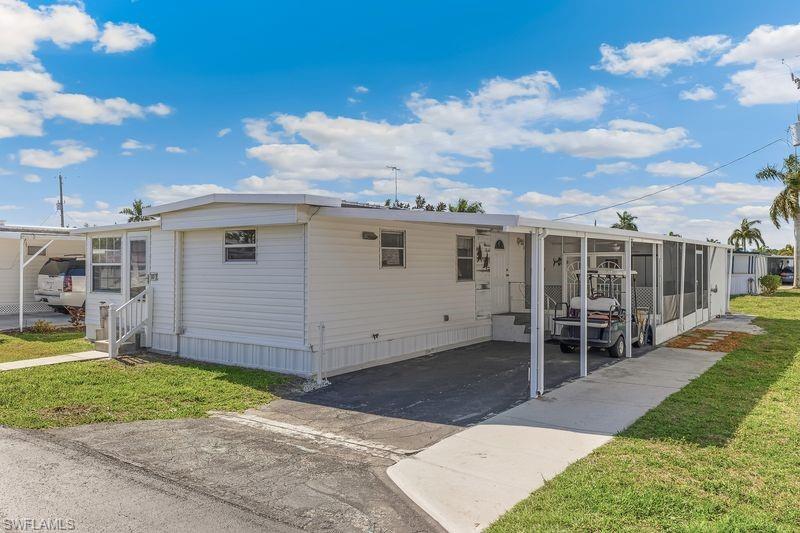 Front of the property with a view of the carport and an additional screened-in patio/storage area in the back.