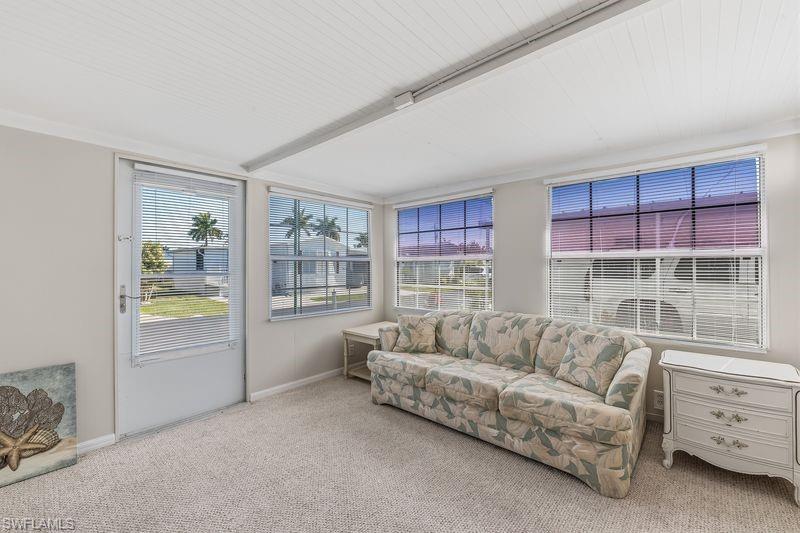 Extra room that could be a potential office/den/ bedroom featuring multiple windows with horizontal blinds, a neutral carpeted floor, and a white beadboard ceiling with exterior door to the outside.