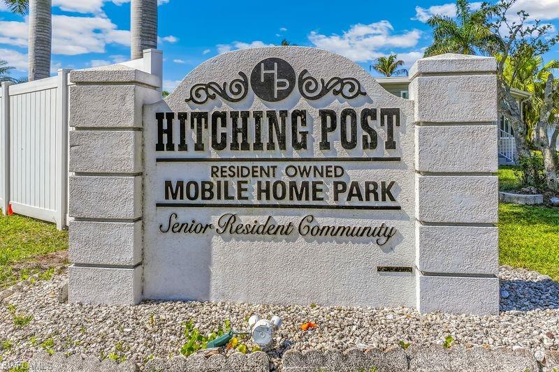 Entrance sign for "Hitching Post Resident Owned Mobile Home Park" with textured stone columns and a decorative arched top.