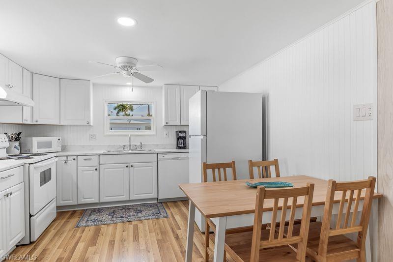 Kitchen featuring updated white cabinetry, white appliances, wood-finish laminate flooring, recessed lighting, and a ceiling fan.