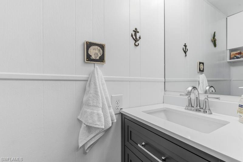 Half bath with white paneled walls that feature a built-in vanity with a white countertop and toilet.