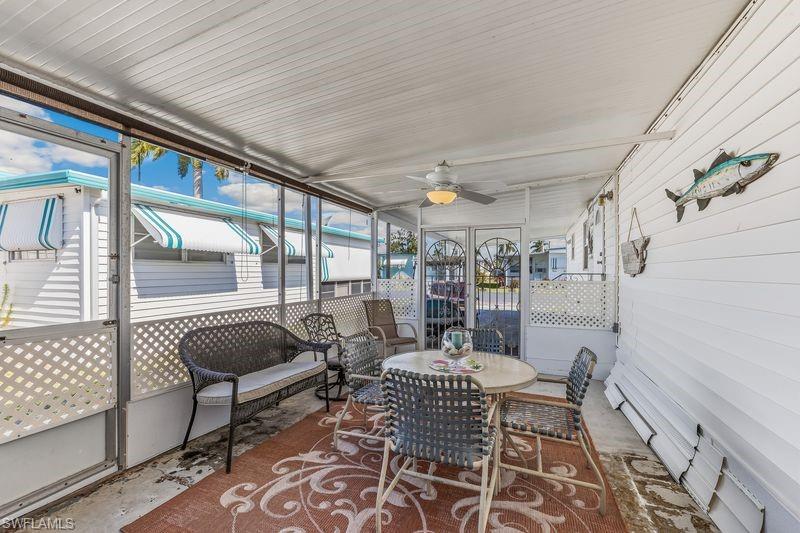 Screened-in porch/lanai featuring a ceiling fan, white paneled walls, and a lattice-patterned screen enclosure.