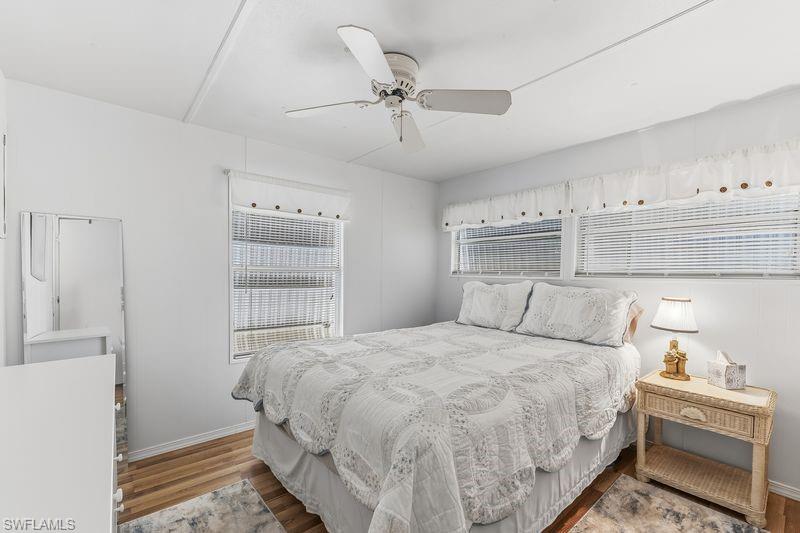 Bright bedroom featuring wood-finish laminate flooring, white walls, and a ceiling fan.