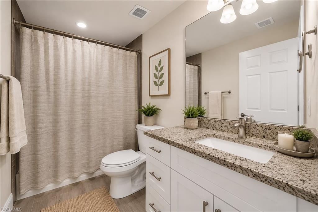 Bathroom featuring a white vanity with a granite countertop, undermount sink, and brushed nickel hardware