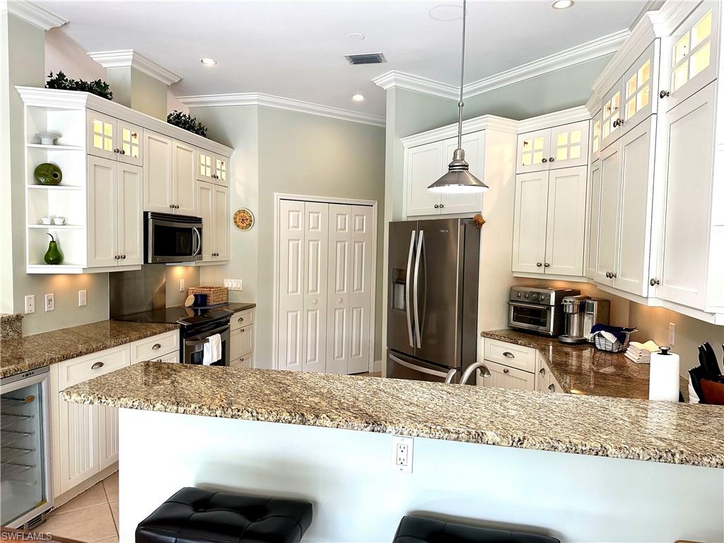 The kitchen features include stainless steel, granite, a wine fridge, a large pantry, and accent lighting.