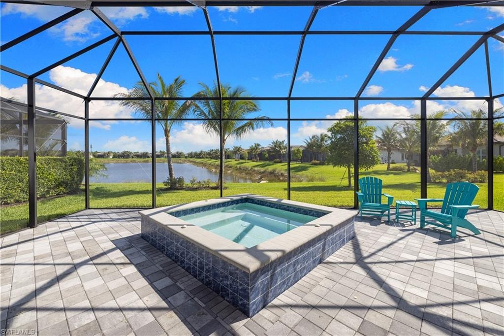 Screened enclosure featuring a built-in spa with blue mosaic tile, a paver patio, and a view of the lake