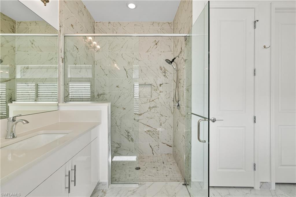 Shower enclosed with a clear glass door and tiled all the way to the ceiling.