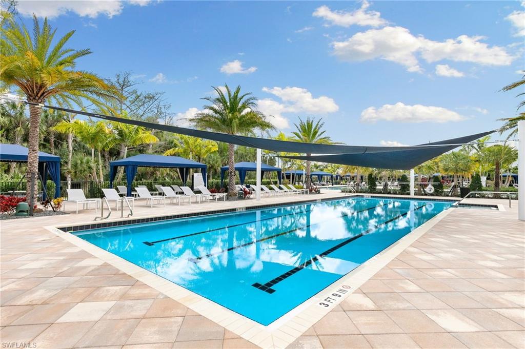 Resort-style swimming pool featuring lap lanes, surrounding lounge chairs, and shaded cabanas