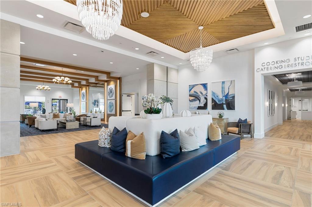 Beautiful and spacious community center common area featuring light-toned wood-finish flooring, a wood-paneled ceiling, and multiple crystal-style chandeliers