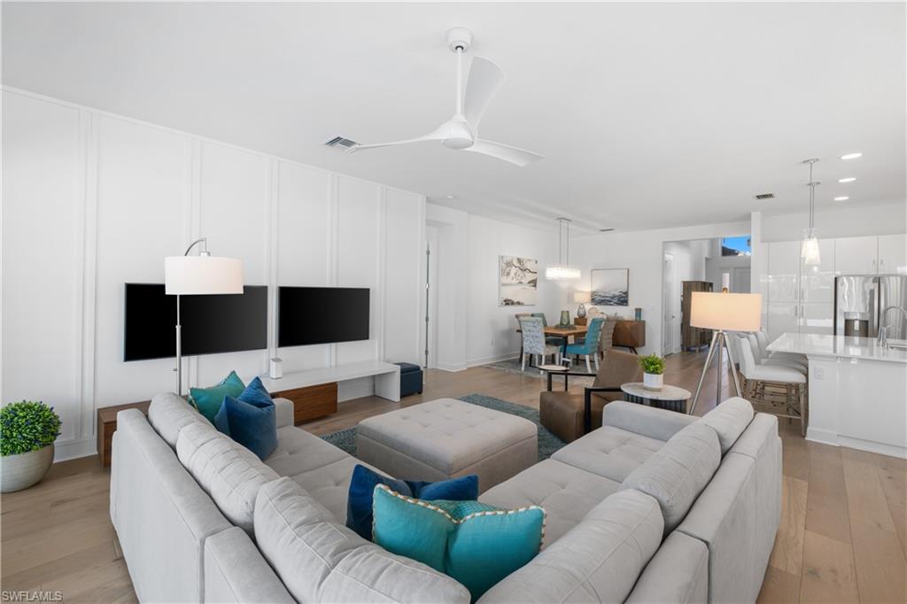 Expansive open concept interior featuring wood-finish flooring, a modern ceiling fan, and recessed lighting