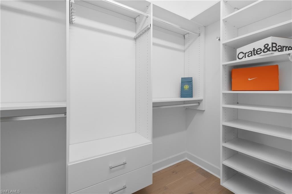 Dual walk-in closets with custom white shelving system featuring multiple hanging rods and integrated drawers