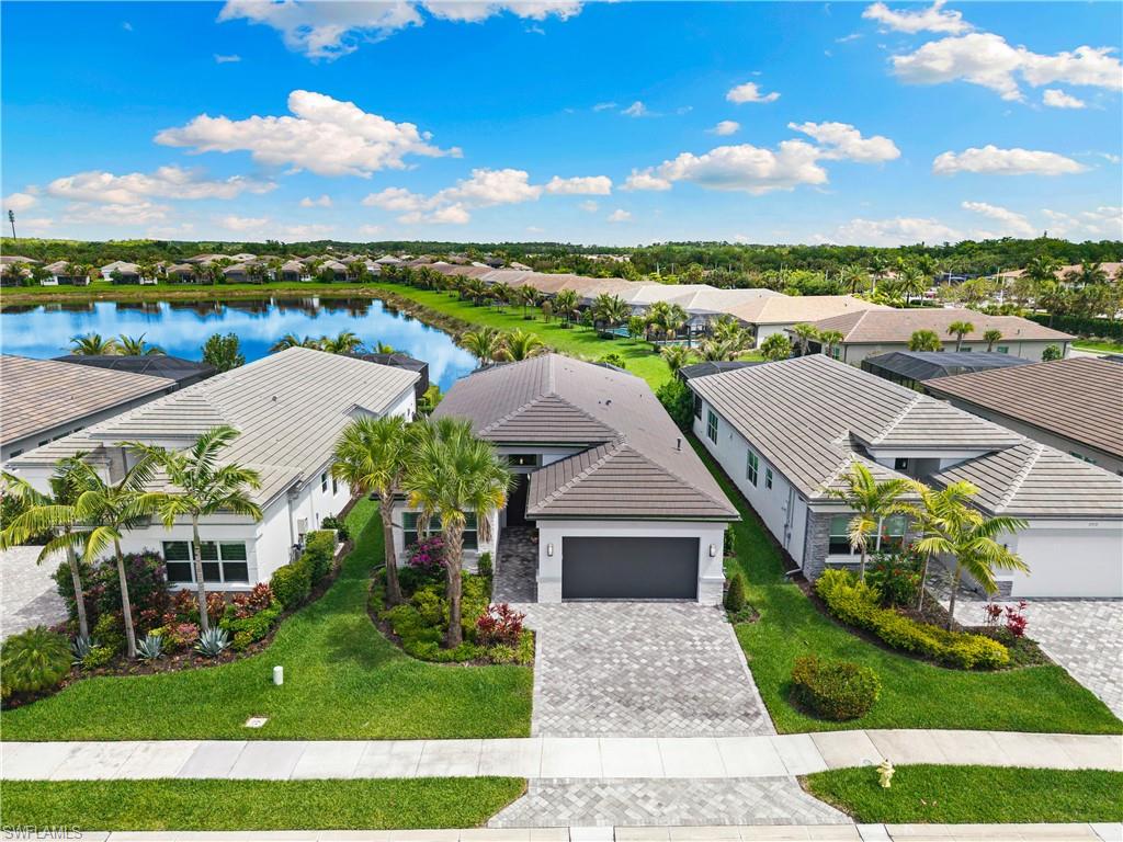 Single-story residence featuring a tile roof, paver driveway, and a two-car garage with a Tesla 3 charger