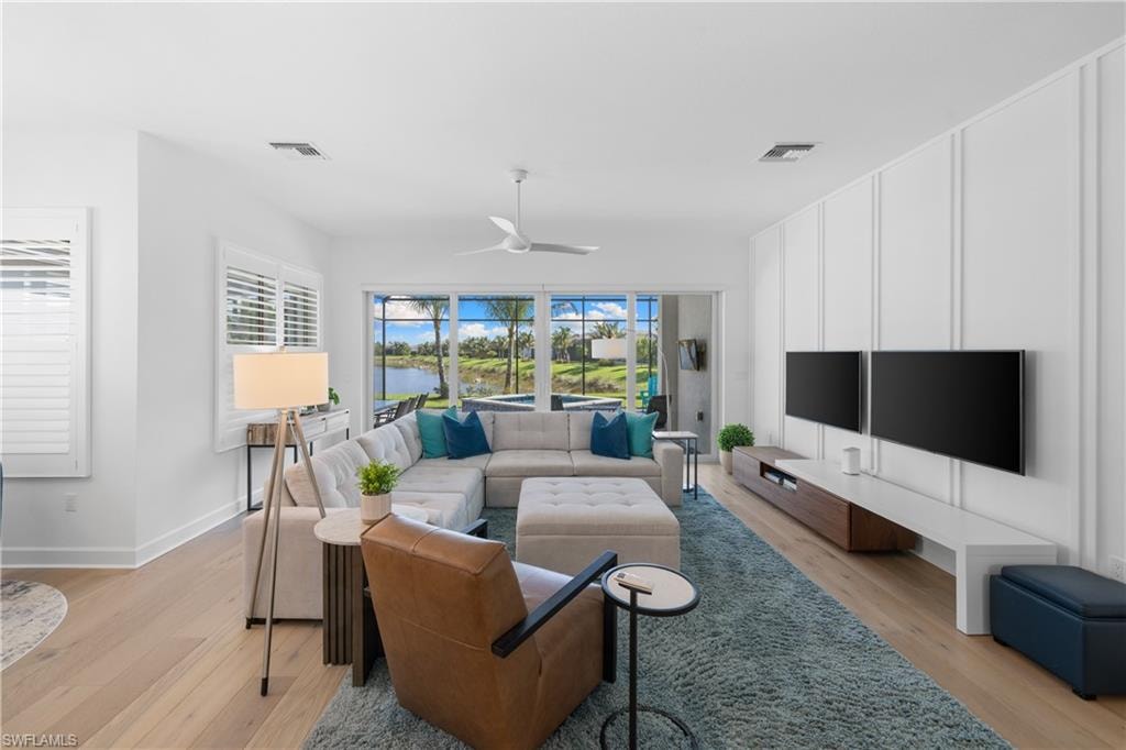 Spacious living area featuring expansive glass sliding doors opening to a screened patio, wood-finish flooring, and a decorative accent wall