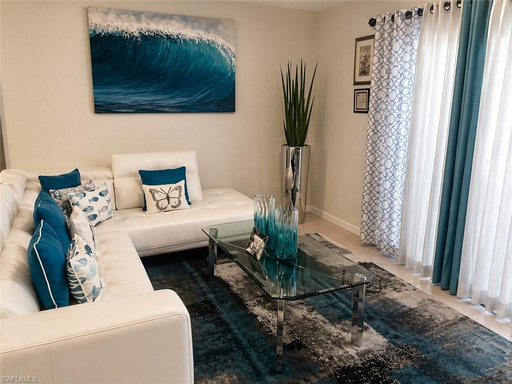 Living area featuring a large window with floor-length curtains, light-toned wall paint, and light-toned flooring