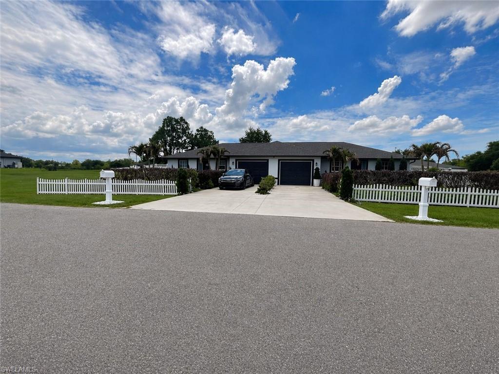 Duplex property featuring a dark shingle roof, white exterior siding, and dark garage doors