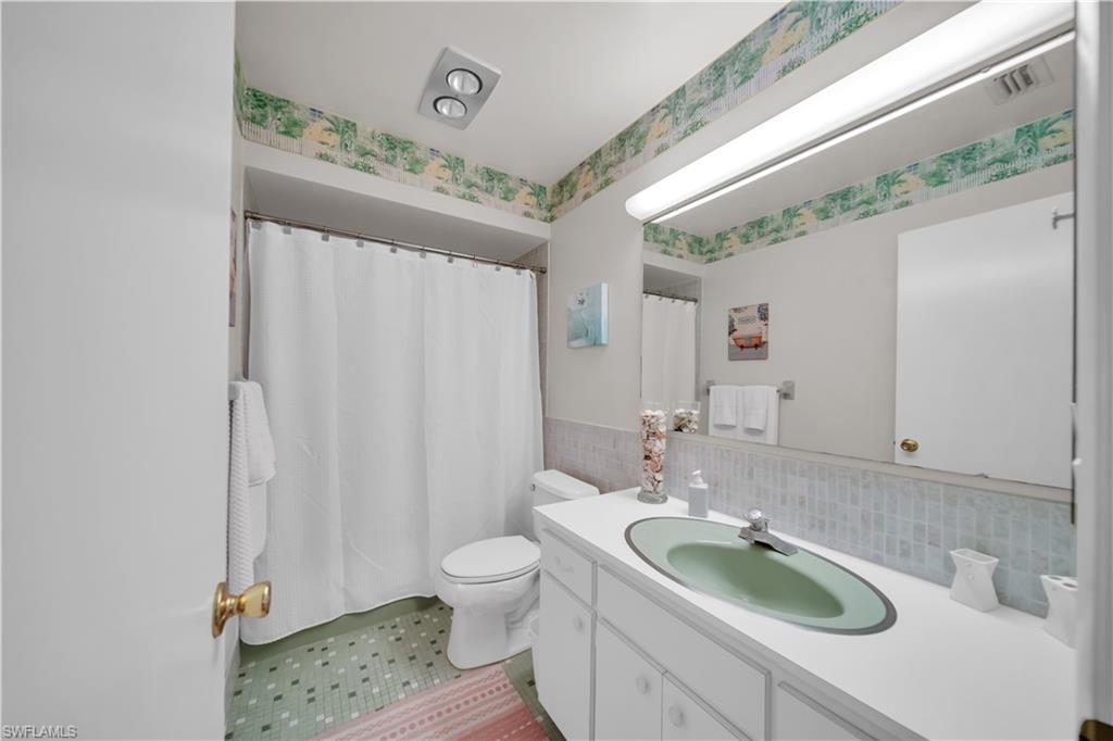 Bathroom featuring a vanity with a green oval sink, a large mirror, and patterned floor tiles