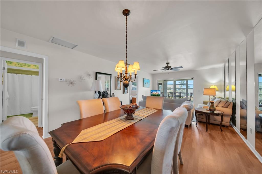 The property features an open-plan dining area with a chandelier and a wooden table, opening into a living space with a ceiling fan and sliding glass doors