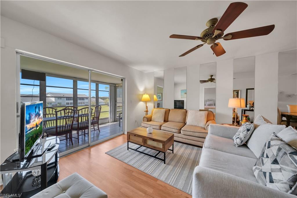 Living area featuring warm wood flooring, a ceiling fan, and sliding glass doors that open to an outdoor screened area