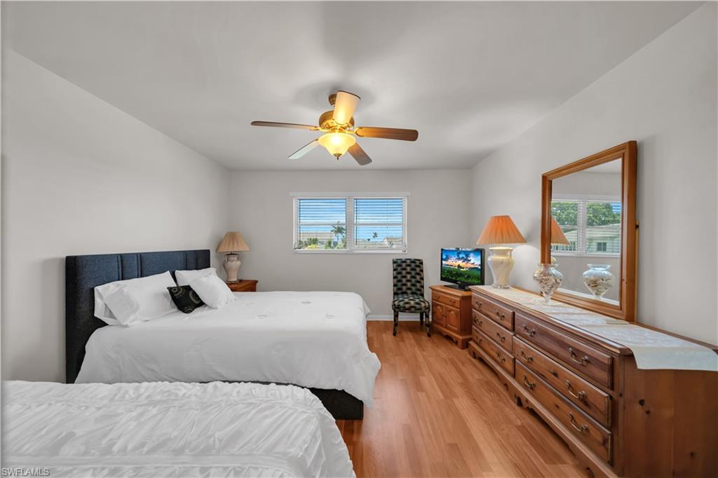 Bedroom featuring light wood flooring, a ceiling fan, and a window with horizontal blinds