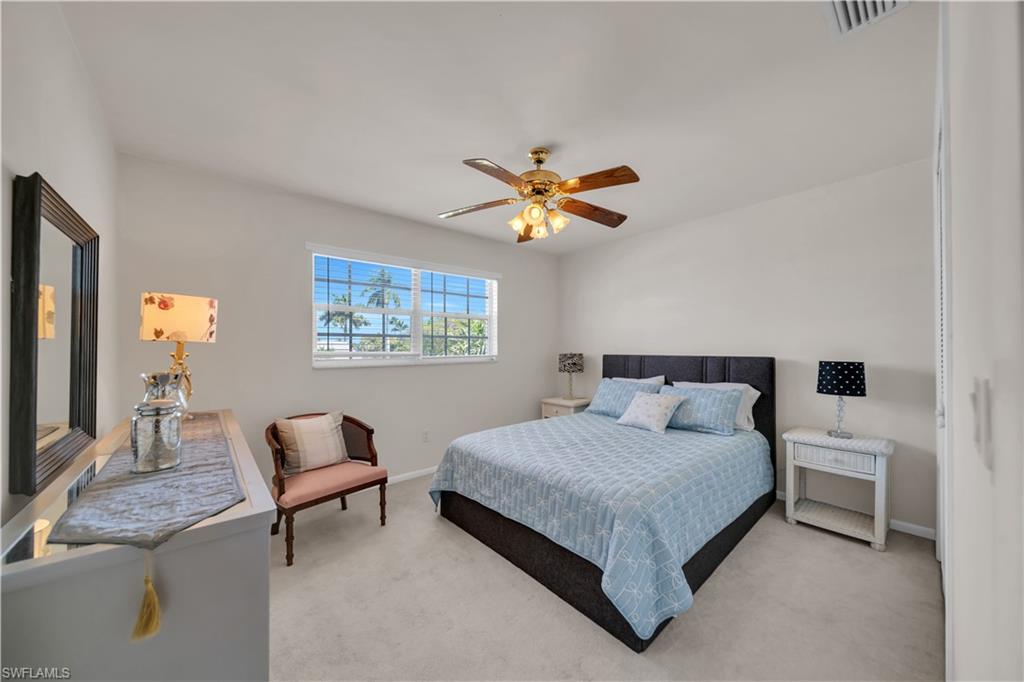 Inviting room with light-colored walls, carpeted floors, a window, and a ceiling fan