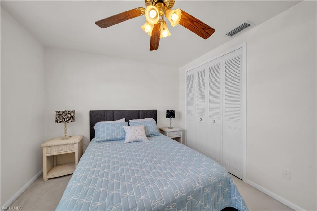 The room features white walls, a ceiling fan with light fixture, and white louvered closet doors
