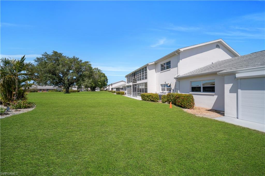 The property features an expansive lawn area with mature trees and landscaping