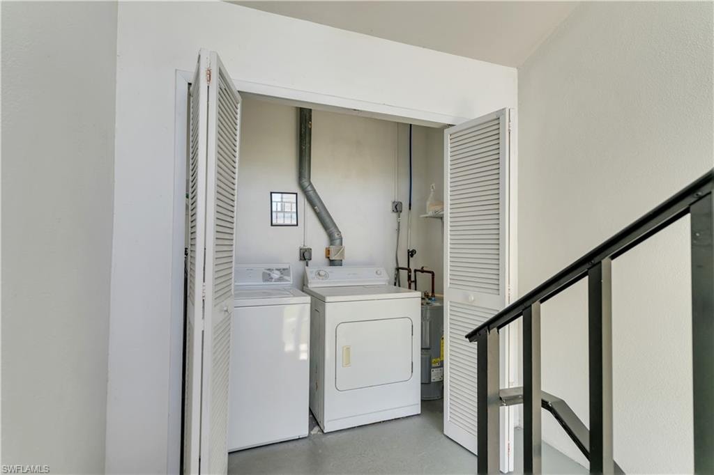 Dedicated laundry area featuring a washer and dryer, white louvered bifold doors, and a water heater