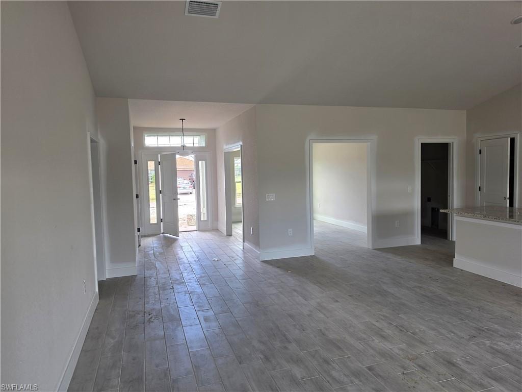 The property features light-colored plank-style flooring throughout the open concept living areas, complemented by a front door with side windows and a transom window
