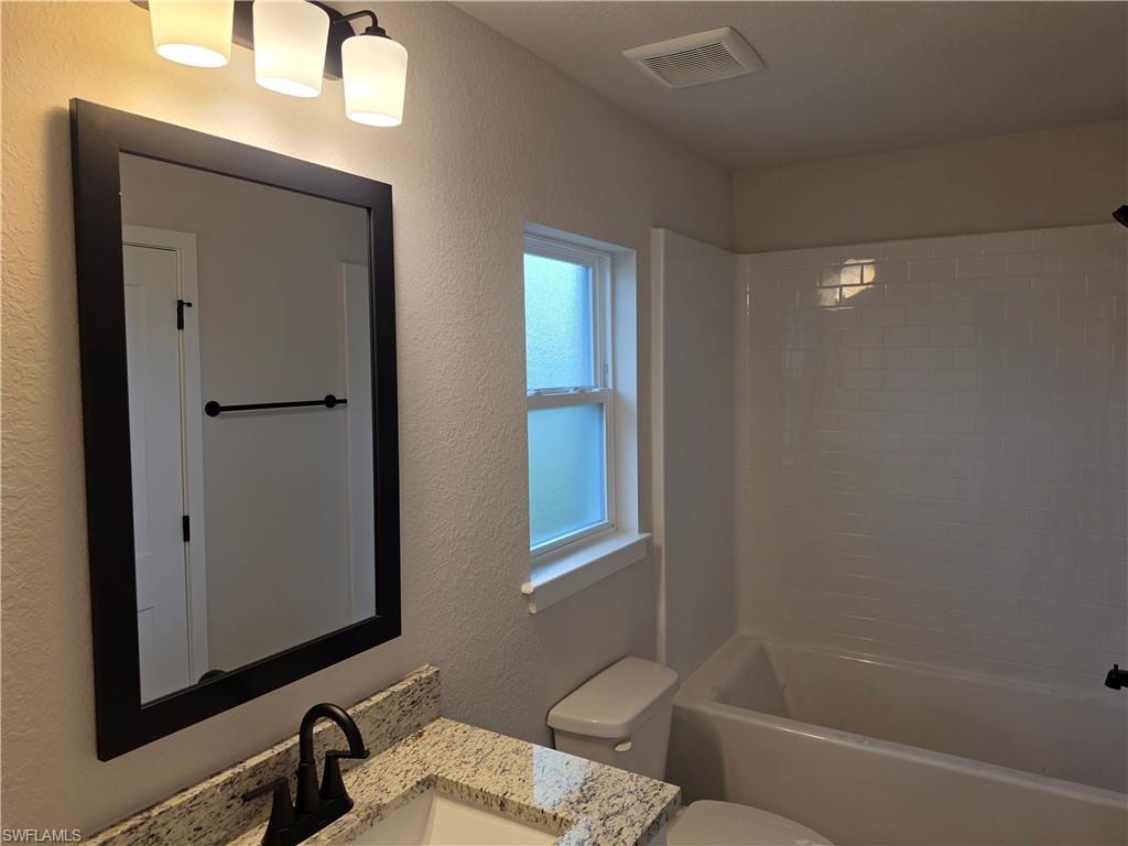 Bathroom vanity featuring a speckled countertop, undermount sink, and matte black faucet