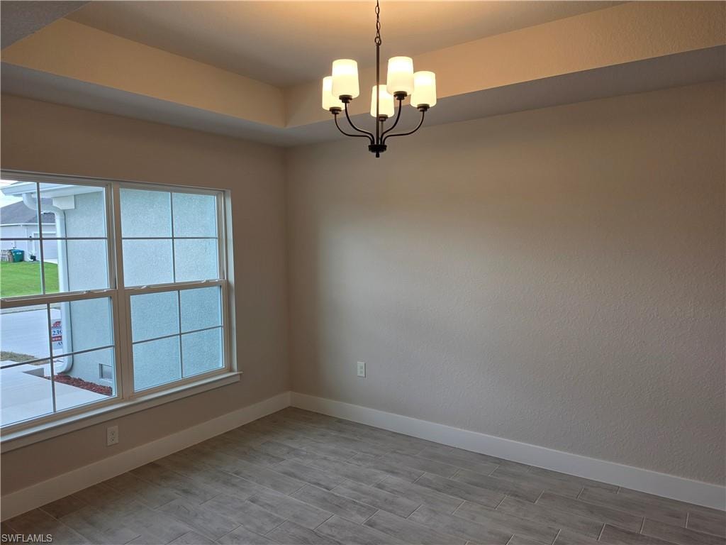 Tray ceiling featuring a contemporary chandelier with frosted glass shades