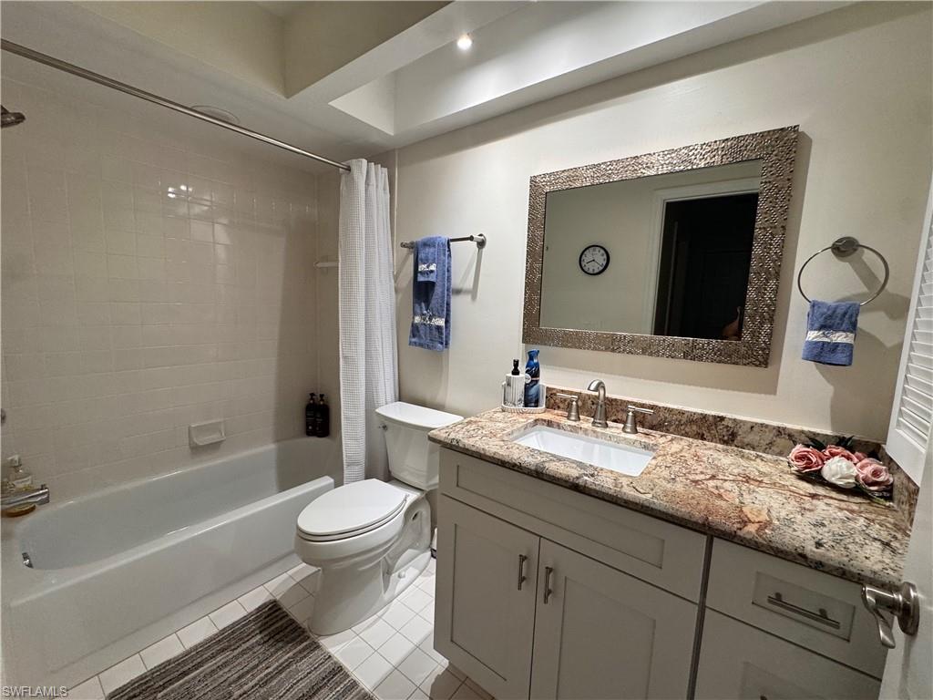 Bathroom featuring a white vanity with a rectangular undermount sink, a polished chrome faucet, and a stone-finish countertop