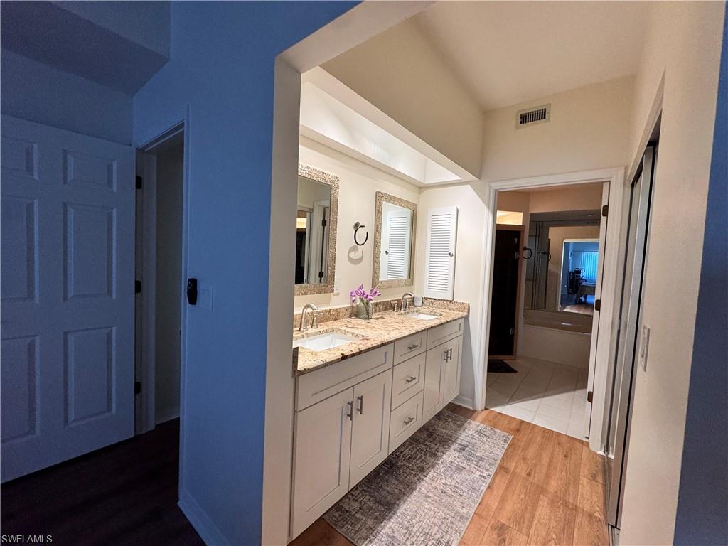 Double vanity featuring light-toned cabinetry, granite countertops, and individual framed mirrors