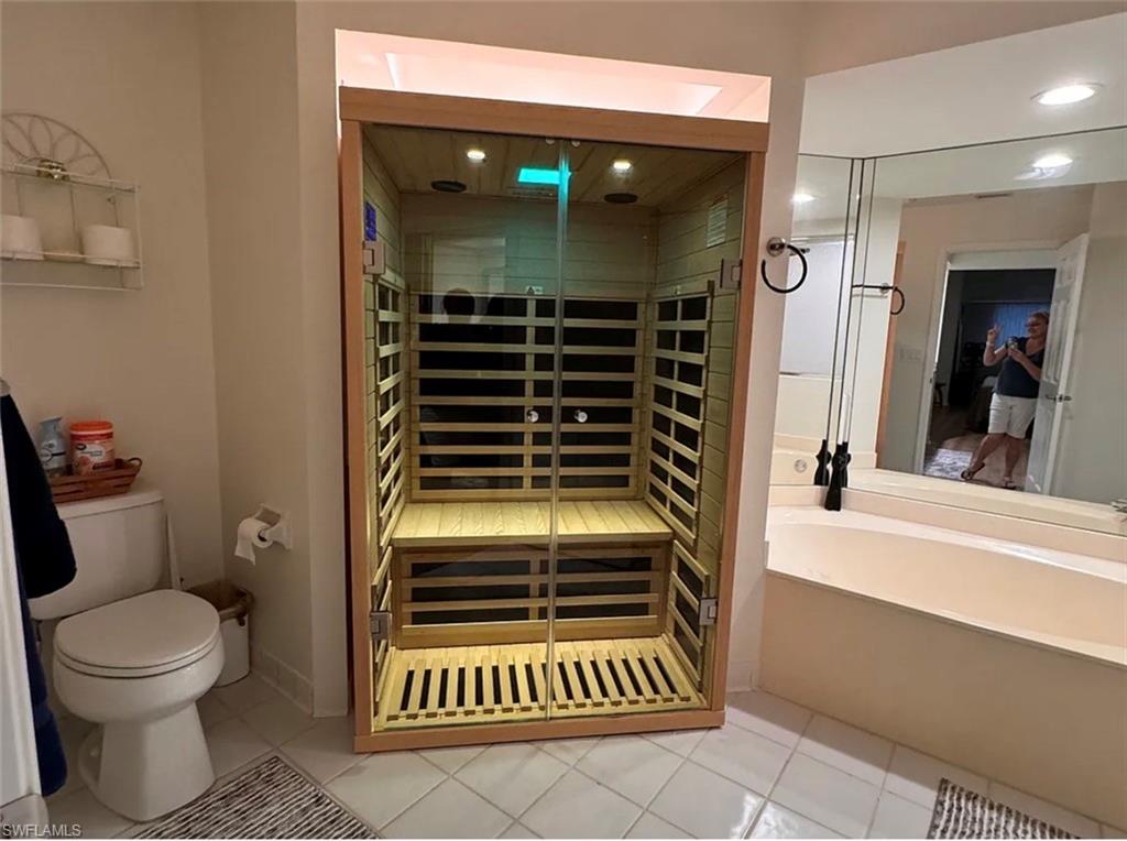 Bathroom featuring a built-in sauna with a glass door, a bathtub, and a toilet