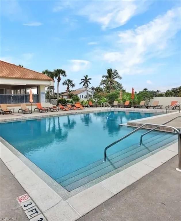 Expansive swimming pool featuring concrete decking, integrated steps, and stainless steel handrails