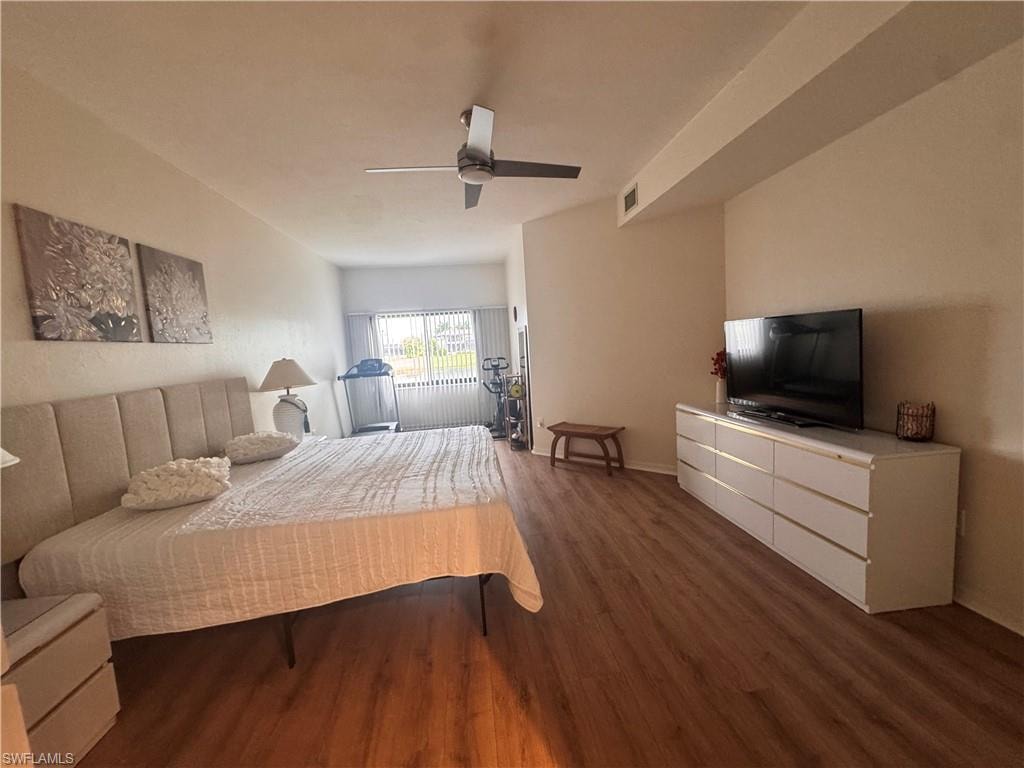The room features wood-look flooring, a ceiling fan, and a window with horizontal blinds
