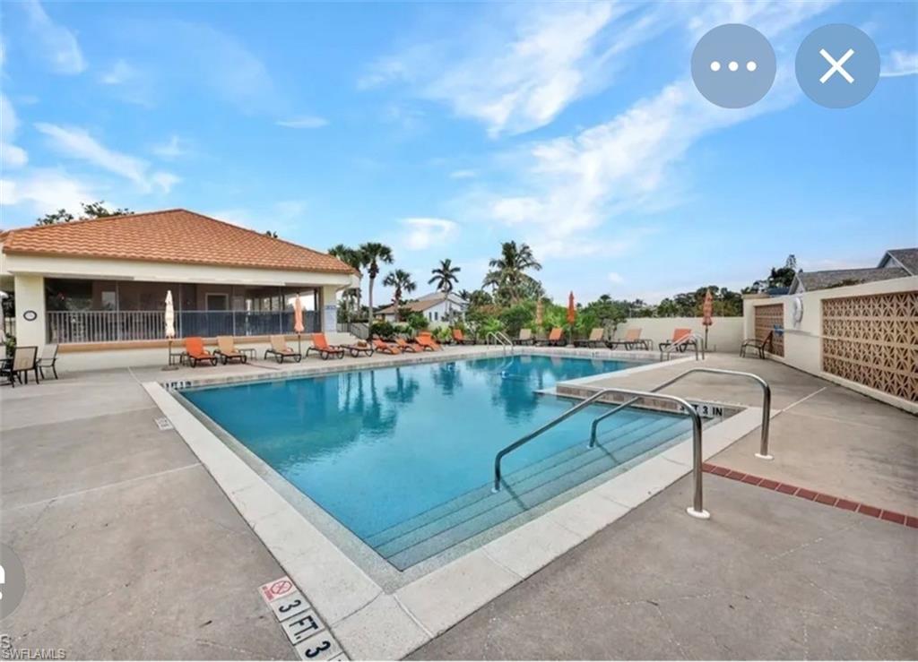 Resort-style pool area featuring a large rectangular swimming pool with integrated steps and stainless steel handrails