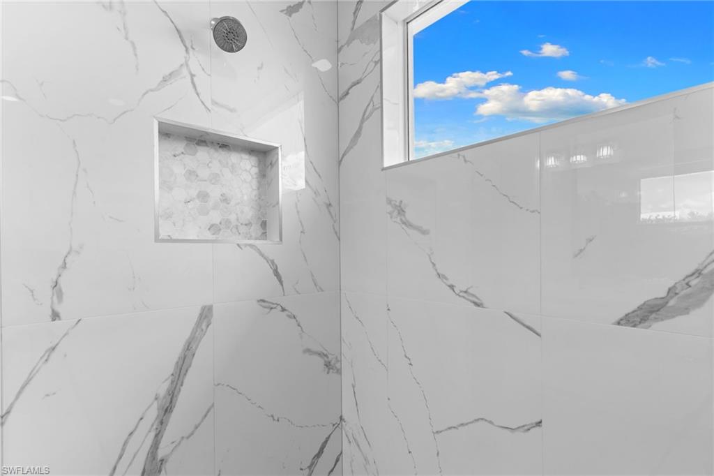 Shower featuring large-format white tile with gray veining, a built-in niche with hexagonal mosaic tile, a ceiling-mounted shower head, and a transom window