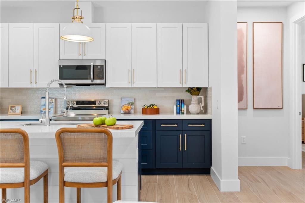 Modern kitchen featuring white upper cabinetry and navy lower cabinetry with gold-finish hardware
