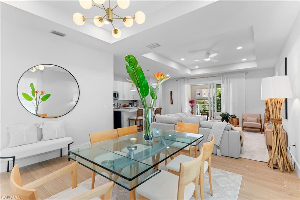 Open-concept dining area featuring light wood-finish flooring and a contemporary chandelier